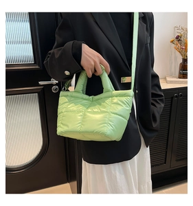 Detail of green quilted puffer shoulder bag with glossy finish and detachable strap