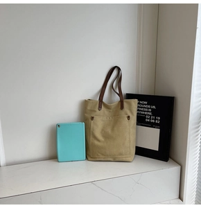 Detail of canvas tote bag showing front pocket with reinforced metal rivet details