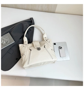 Flat lay of cream white tote bag with lychee texture, zippers, and fashion accessories