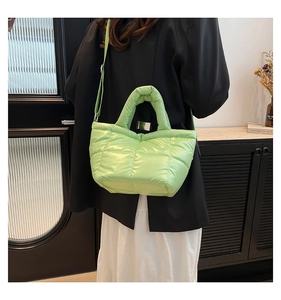 Quilted green puffy handbag shown as a crossbody bag with adjustable nylon shoulder strap