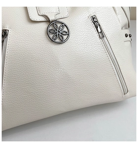Close-up of white lychee pattern leather tote bag with silver zipper and floral metal pendant