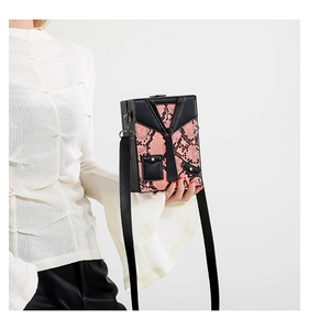 Detail of pink snakeskin box bag with creative tuxedo suit design on white background