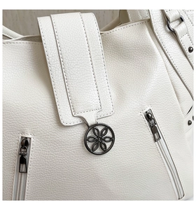 Detail of lychee pattern beige PU leather tote with floral metal charm and zipper accent