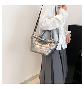 Detailed view of silver metallic quilted puffer handbag with reflective finish and stitching