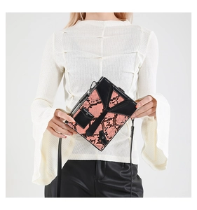 Detail of trendy box crossbody bag featuring orange snake pattern and geometric leather patchwork