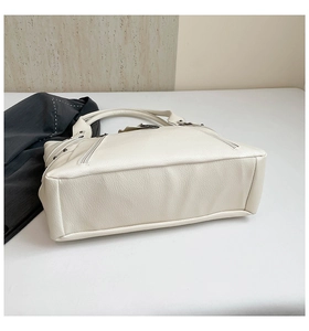 Detailed side view of off-white faux leather tote bag showing side zipper and rivet details