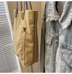 Detail view of khaki canvas tote bag showing side width and vintage metal rivet stud