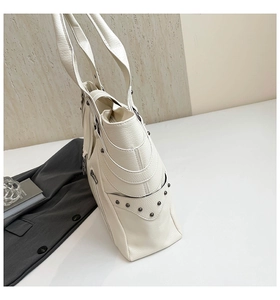 Detail of off-white tote bag showing side zipper pocket and grey rivet studs decoration