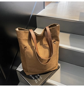 Detail of vintage canvas tote bag with brown leather handles and a riveted front pocket