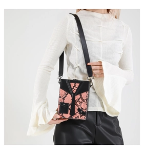 Detail of pink snake skin crossbody bag featuring a creative suit-style design on model
