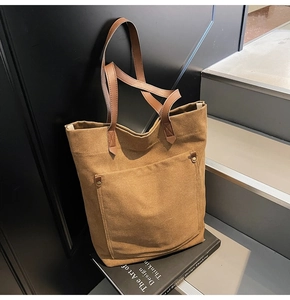 Brown canvas tote bag with leather handles resting on a design book on modern steps