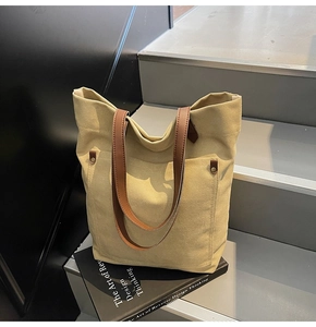 Close-up of vintage canvas tote bag with brown leather straps and rivet details
