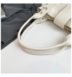 Detail of cream pebbled leather tote bag showing sturdy handles and metal rivets