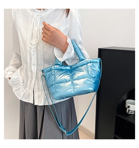 Close-up of a bright blue quilted down bag featuring shiny fabric and a detachable strap