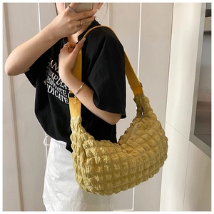 Detail shot of yellow hobo bag with bubble texture and canvas strap on a model