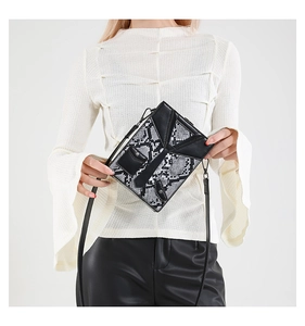 Detail view of snakeskin pattern crossbody bag worn by model on minimalist white background