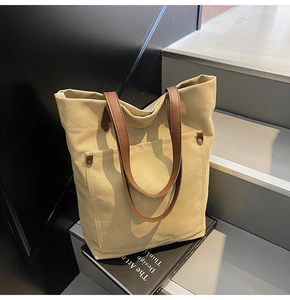 Detail of canvas tote bag with front pocket and leather handles on a decorative book