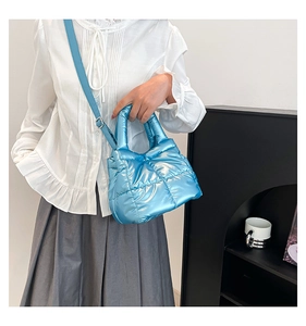 Detailed close-up of shiny blue quilted padded handbag with adjustable strap