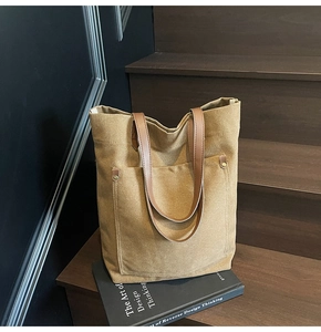 Macro detail of canvas tote with brown leather handles and metal rivets on stairs