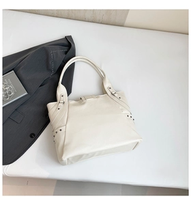 Detail view of white lychee grain leather tote bag with metallic rivet and strap accents