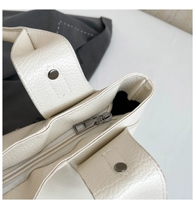 Detail of lychee textured leather tote bag featuring a gun-metal zipper and round rivets