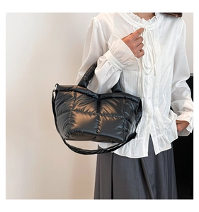 Detailed close-up of quilted black nylon tote bag with puffy down-filled texture on model