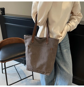 Detail of vintage washed canvas tote bag with leather handles and metal rivet pocket