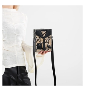 Detail of box crossbody bag featuring snake pattern print and unique suit design with tie