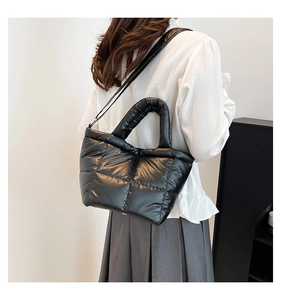 Detail of black quilted puffer tote bag with glossy nylon finish and shoulder strap