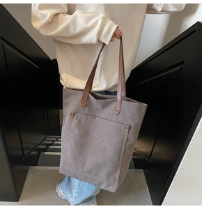 Detail view of khaki canvas tote bag with brown leather handles and metal rivets