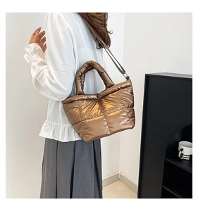 Detail of metallic bronze quilted puffer bag with glossy finish and dual strap design