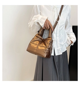 Quilted bronze down puffer tote bag styled as a shoulder bag on a female model