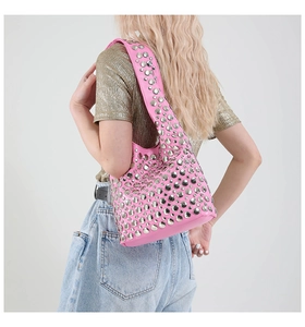 Rosafarbene Punk-Schultertasche mit silbernen Nieten, getragen von einem Model