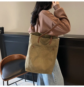 Macro view of olive green canvas tote bag with brown leather straps and front pocket