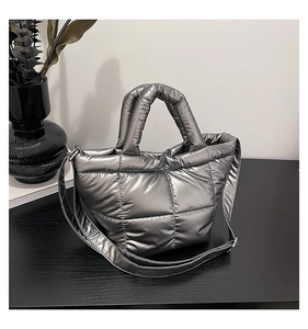 Detail of silver quilted puffer tote bag with metallic finish and adjustable shoulder strap
