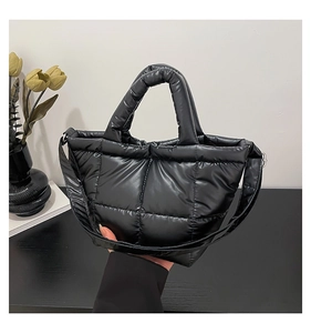 Detail of black quilted puffer tote bag with soft padded handles and nylon texture