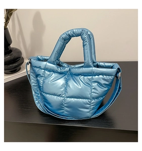 Detail of metallic blue quilted down bag showing the handle and square stitching texture