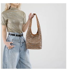 Braune Leder-Tote-Bag mit silbernen Nieten, getragen von einem Model im modischen Outfit