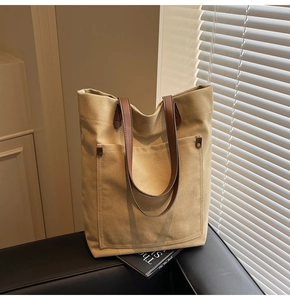 Detail of canvas tote bag with front pocket and contrast brown leather handles
