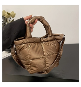 Detailed view of bronze quilted puffer tote bag with metallic finish and wide shoulder strap
