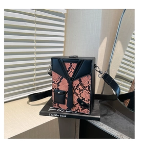 Detail of box crossbody bag featuring pink snake print and creative suit tie design