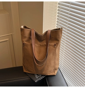 Close-up of vintage canvas tote bag with brown leather handles and rivet detail pocket
