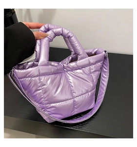 Close-up of light purple quilted puffer handbag with glossy metallic nylon texture