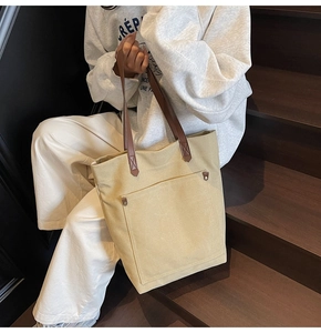 Detail of canvas tote bag featuring a large front pocket and metal rivet reinforcement