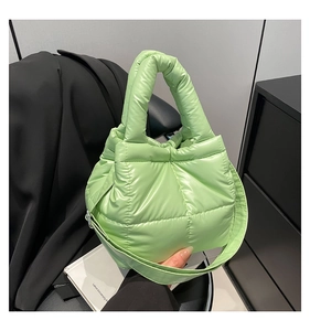 Detailed close-up of light green quilted down tote bag with metallic glossy fabric