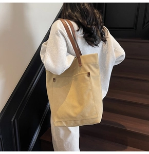 Detail of vintage canvas tote bag with brown straps and rivets on a wooden staircase