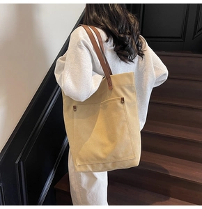 Detail of khaki canvas tote with metal rivets and brown leather shoulder strap handle