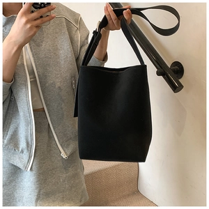 Detail einer minimalistischen schwarzen Beuteltasche mit breitem Schultergurt und Metallschnalle