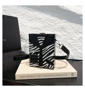 Detailed view of square hard-shell crossbody bag with zebra print and suit tie design