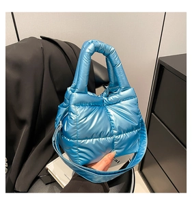 Detail of bright blue quilted down fabric tote bag with glossy finish and top handle